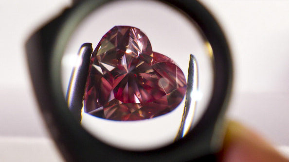 heart shaped purplish pink diamond through the jewellers loupe