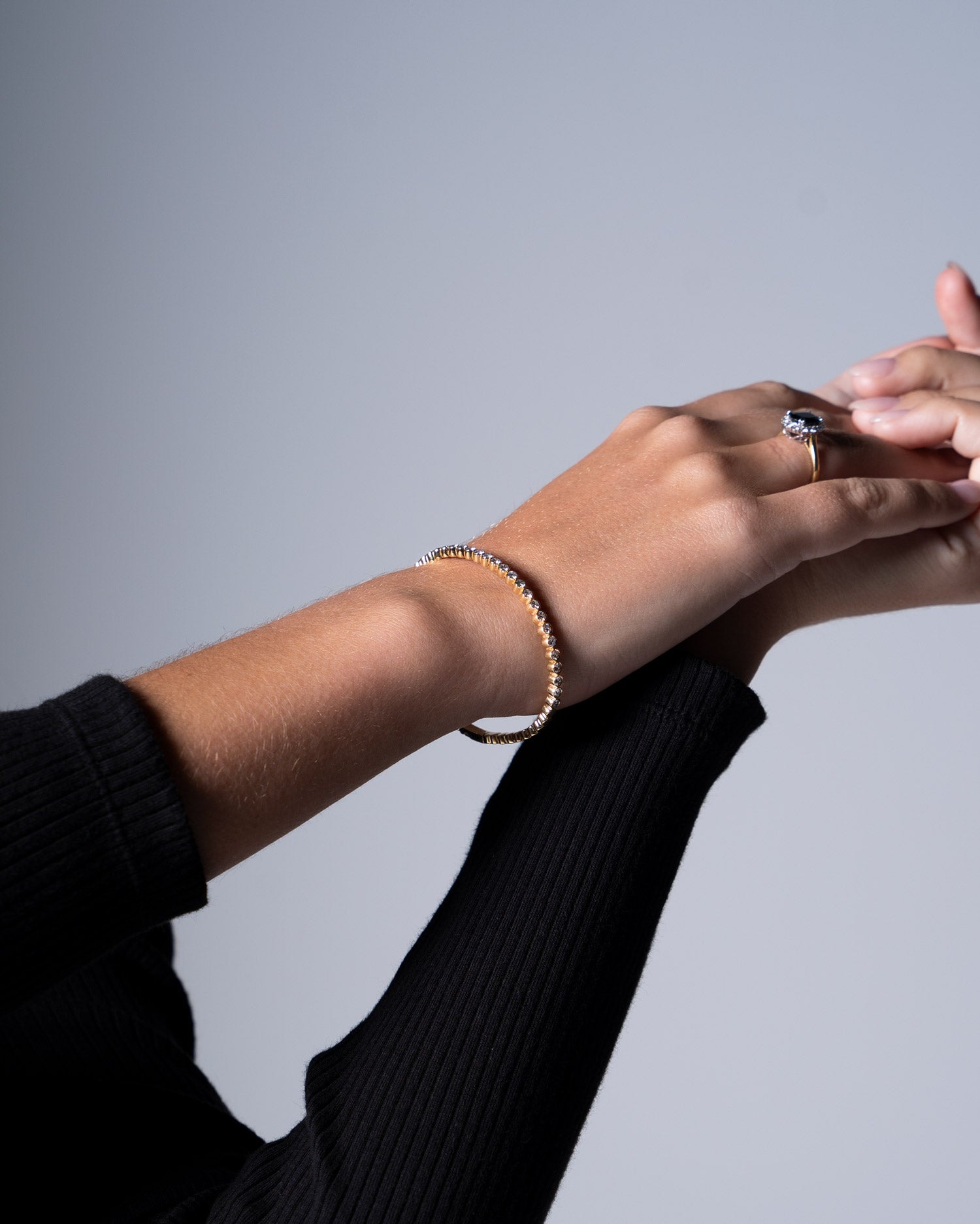 diamond bezel set flexi bangle on model wearing black long sleeve t shirt and also featuring the 'diana' sapphire ring on finger.