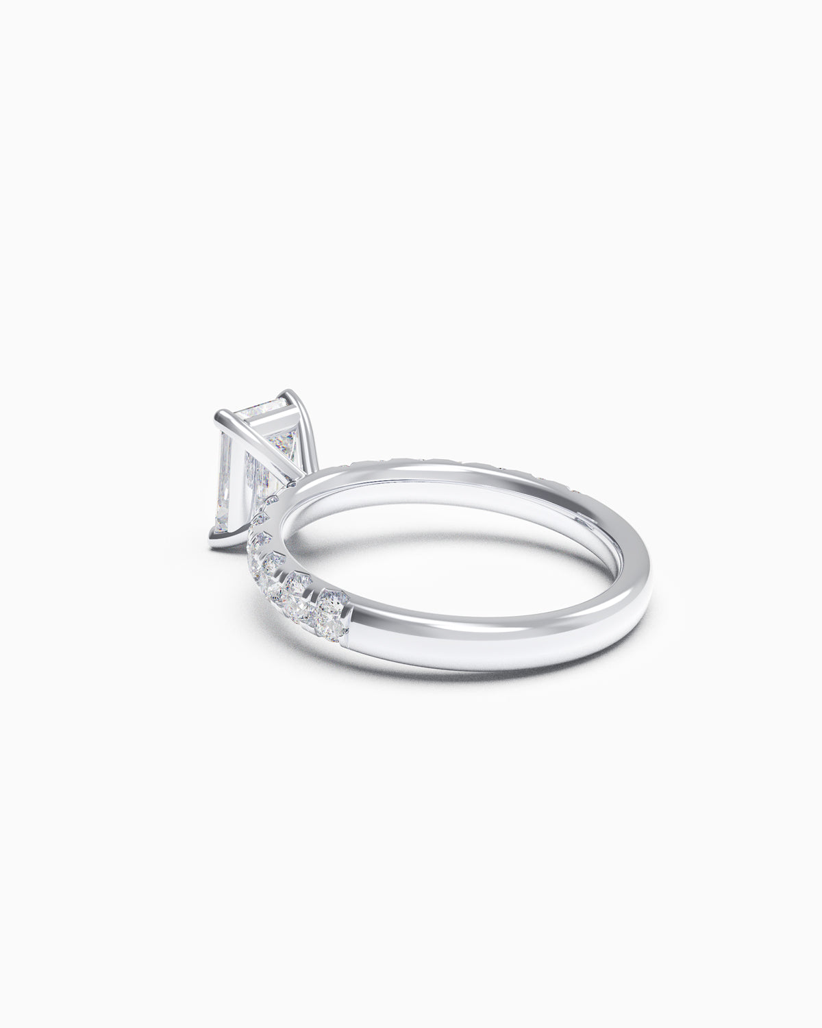 Side view of a solitaire emerald-cut diamond ring with a French-set band, showcasing low-profile claws and intricate side detailing.