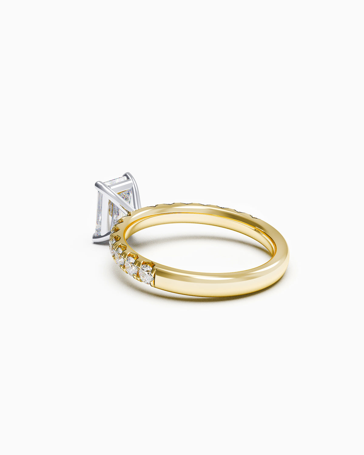 Side view of a solitaire emerald-cut diamond ring with a French-set band, showcasing low-profile claws and intricate side detailing.