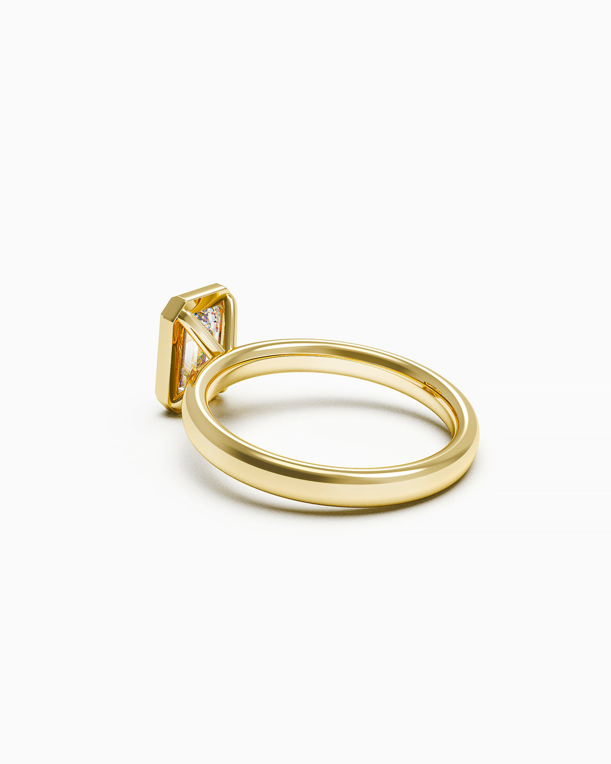 side view of A yellow gold engagement ring with a vertically set emerald-cut diamond in a bezel setting, photographed on a white background.
