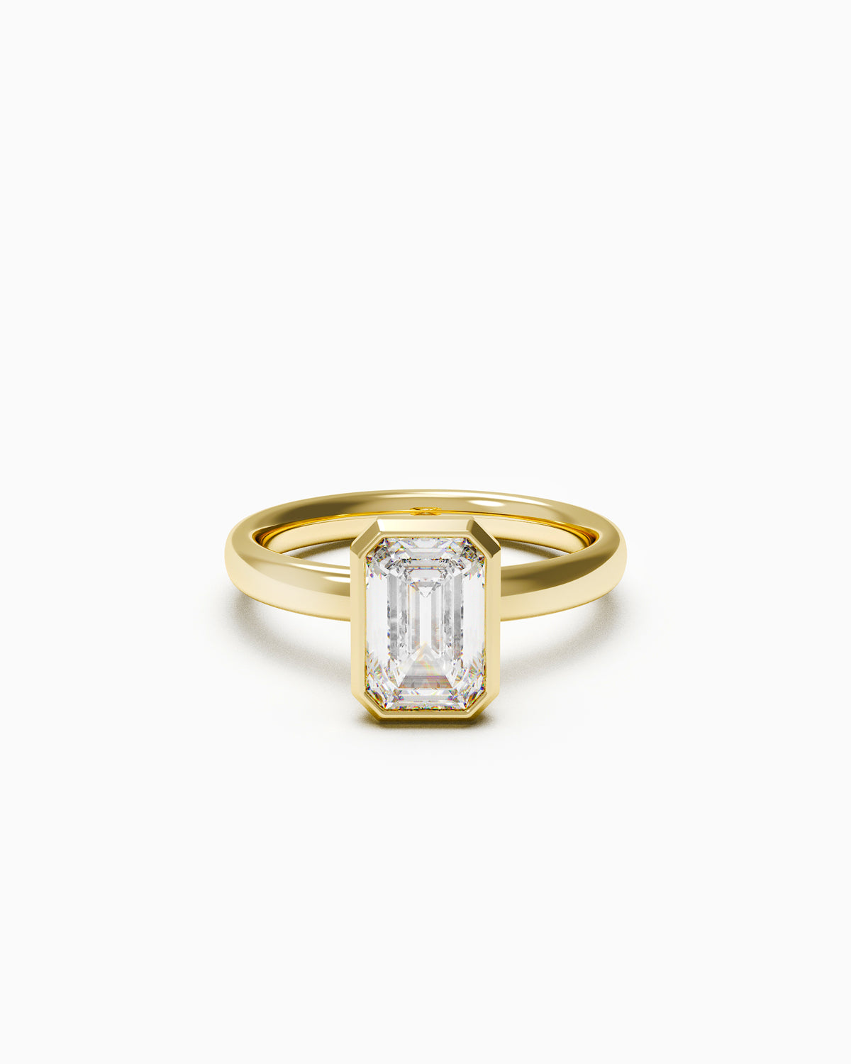 A yellow gold engagement ring with a vertically set emerald-cut diamond in a bezel setting, photographed on a white background.