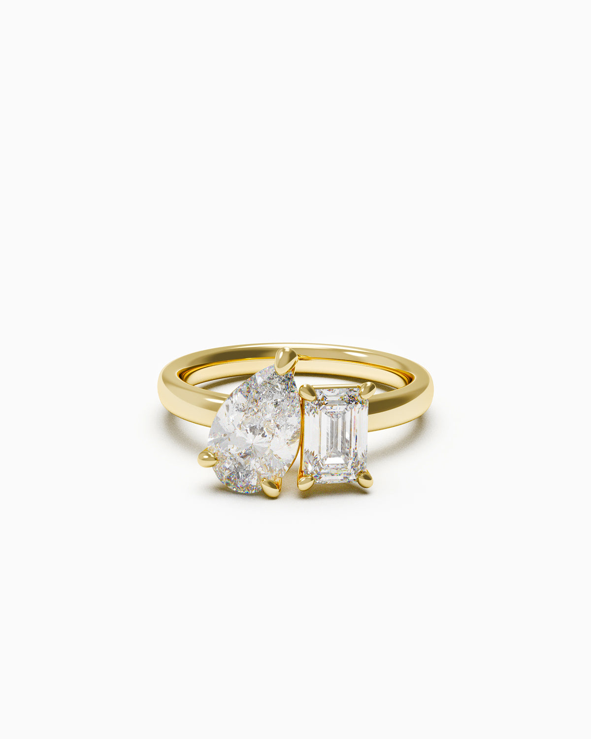 A two-stone engagement ring featuring a pear-cut and an emerald-cut diamond, set in yellow gold