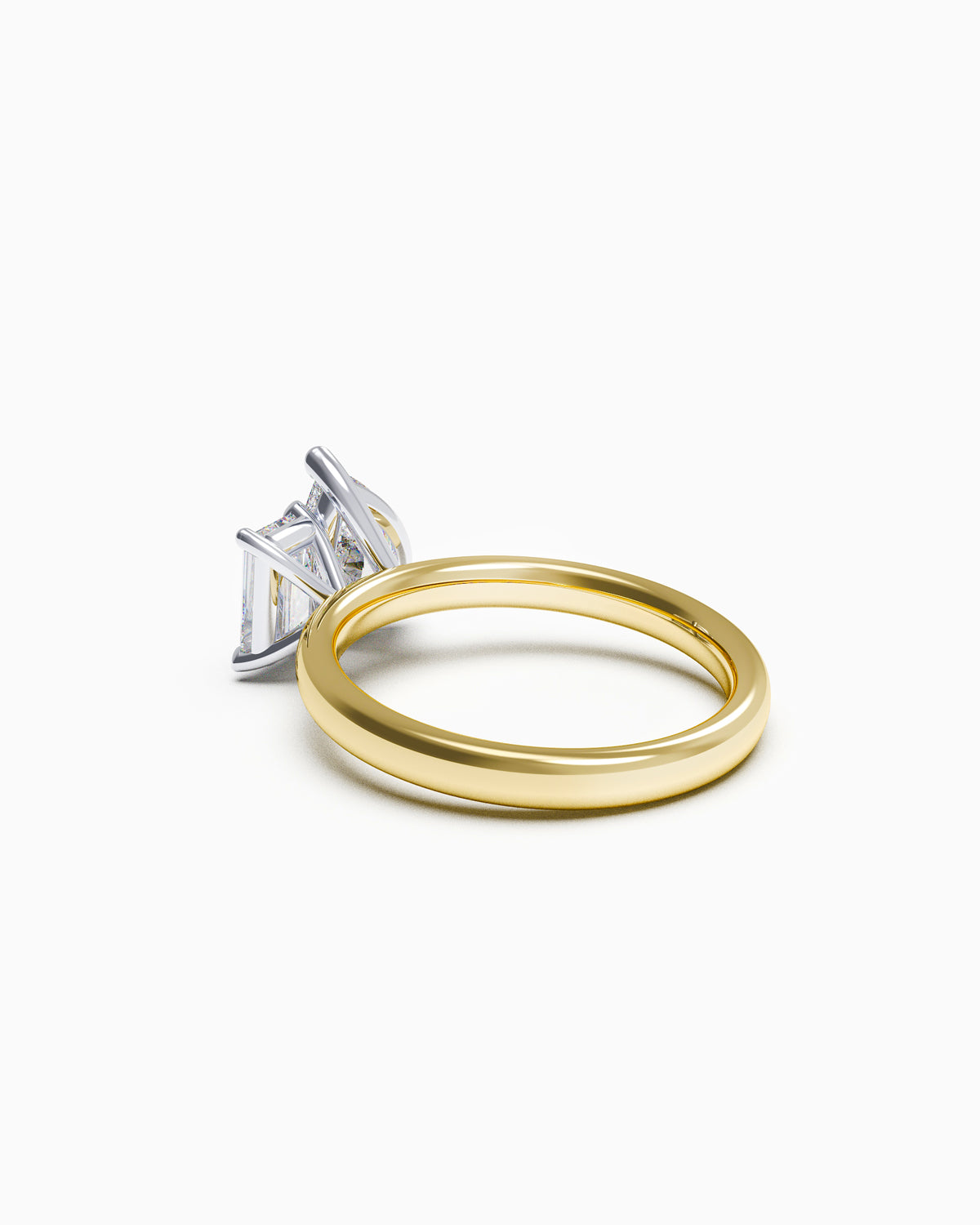 A two-stone engagement ring featuring a pear-cut and an emerald-cut diamond, set in yellow and white gold, side view