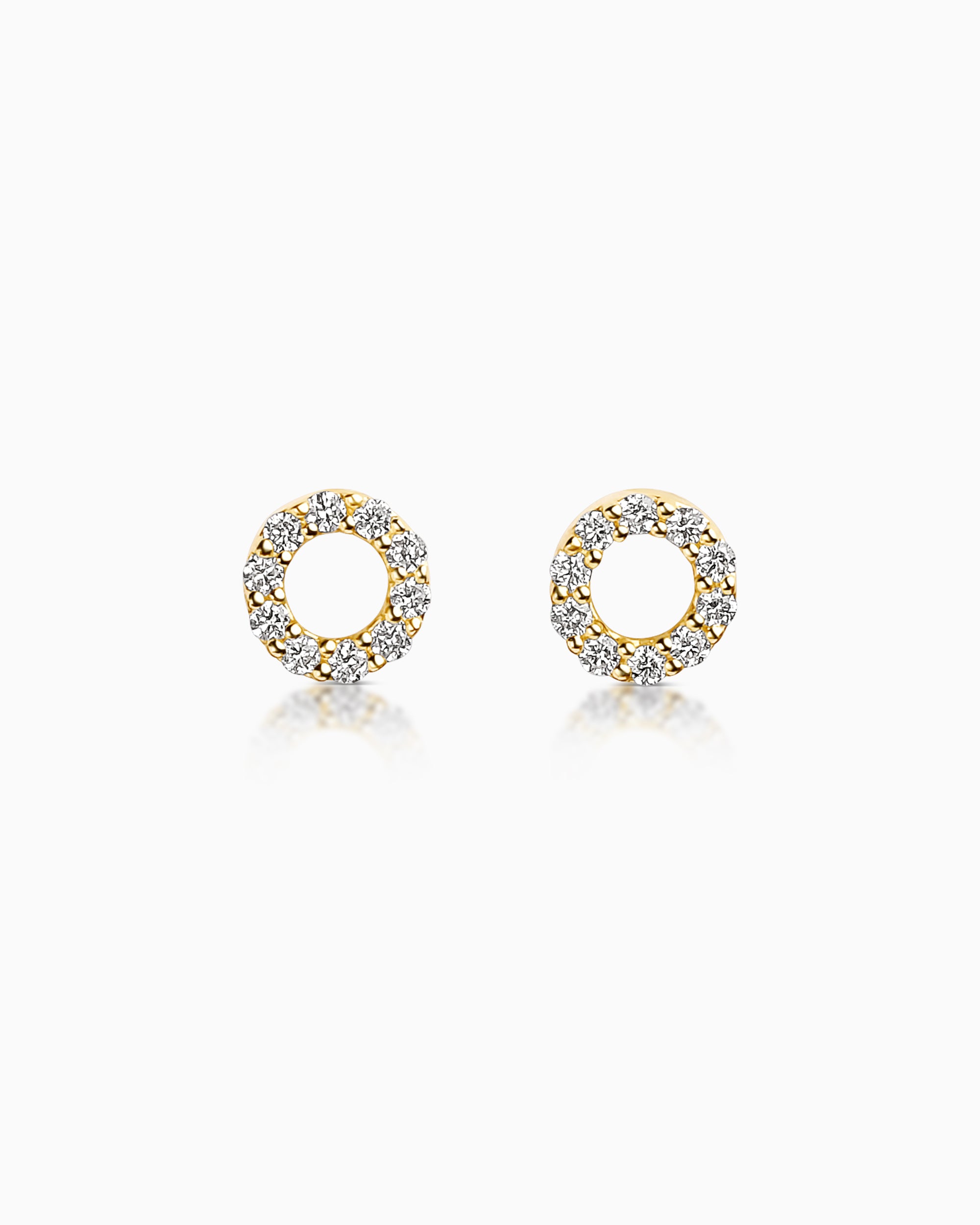 Small circular diamond stud earrings in 18k yellow gold with round brilliant diamonds in a prong setting forming an open circle design.