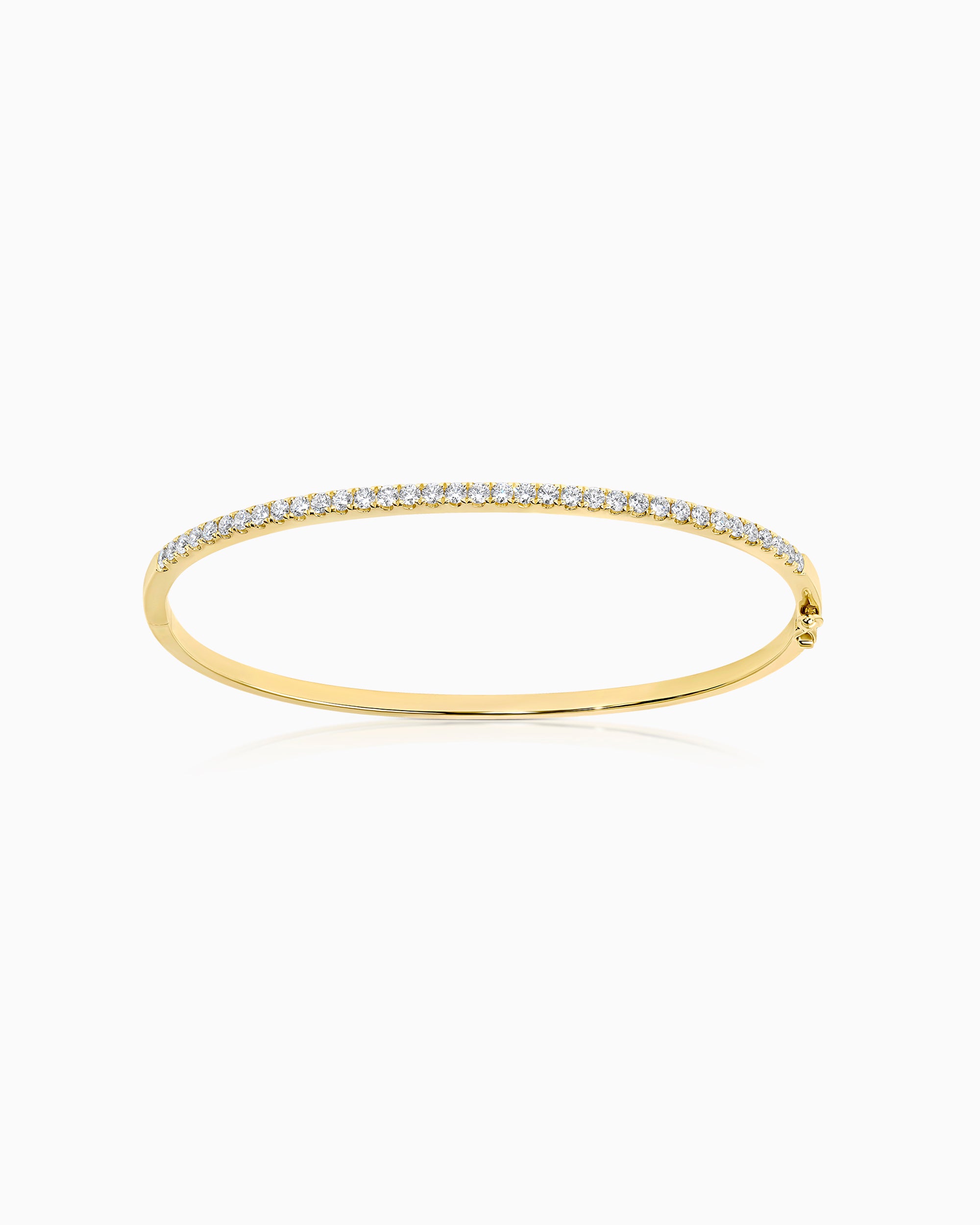 18k yellow gold half-set diamond bangle with scallop-set round brilliant diamonds across the upper arc and a plain polished underside, with box clasp, photographed on a light grey background