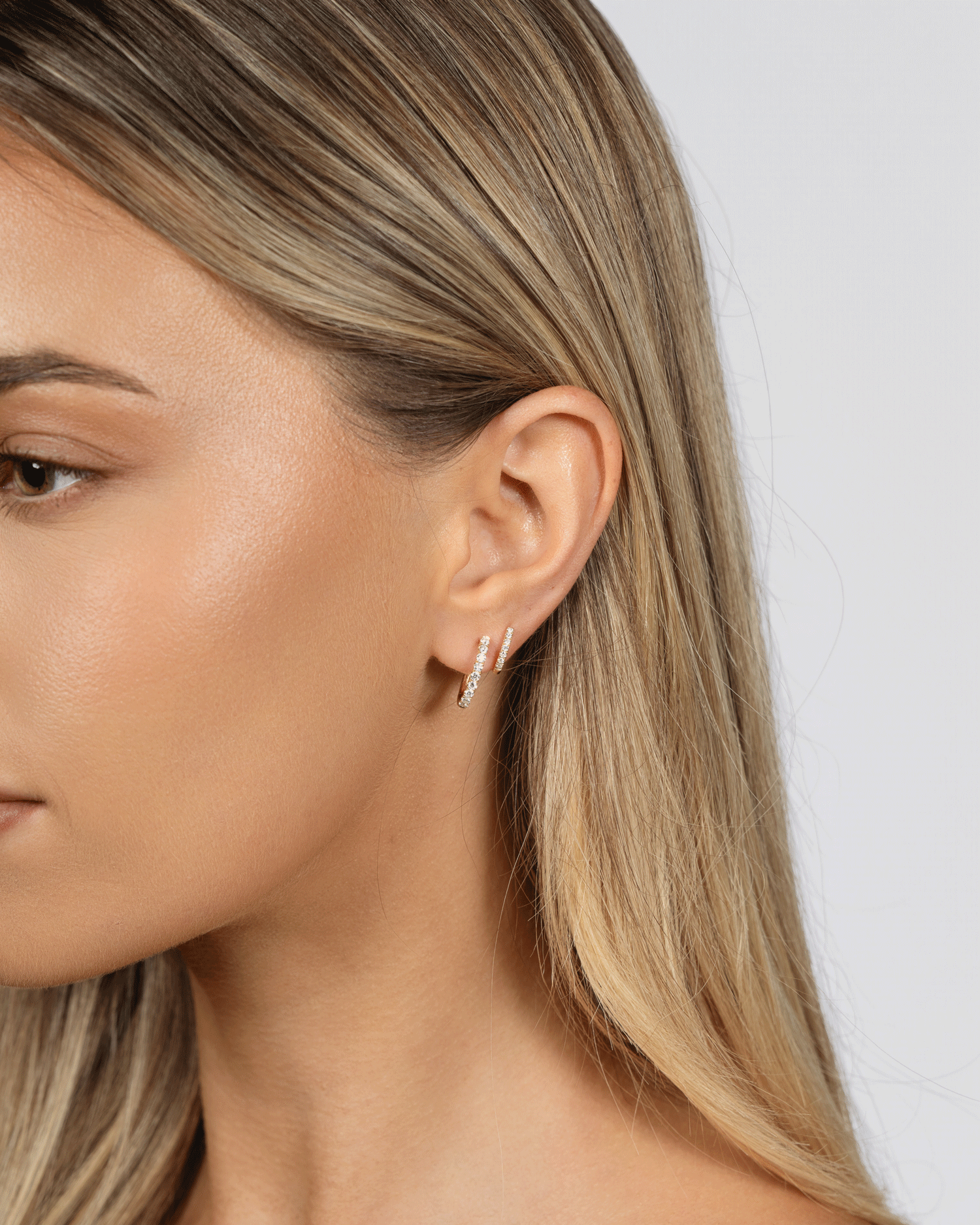Close-up of a person wearing a silver earring with a plain background