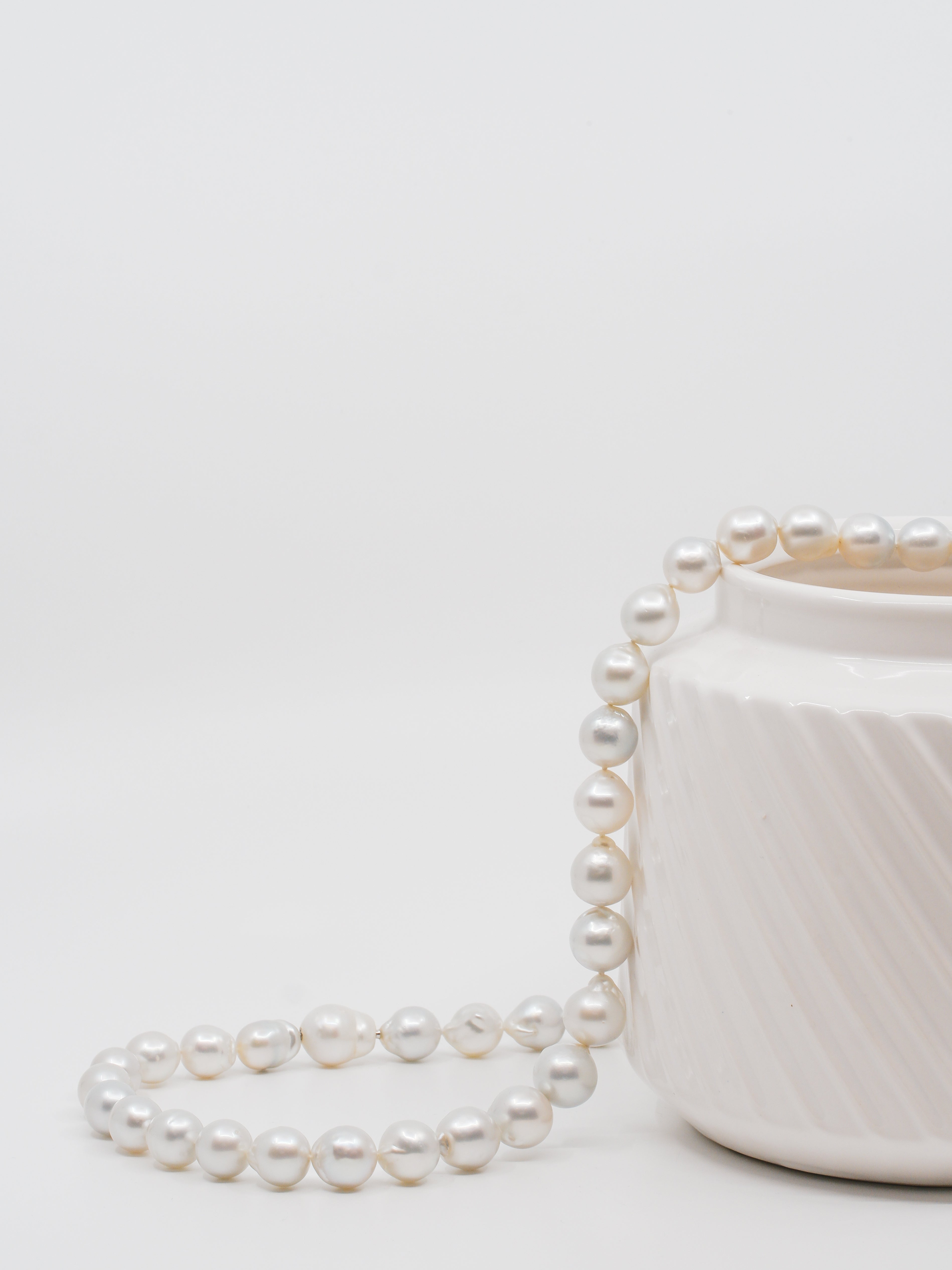 australian south sea pearl strand draped over white vase.