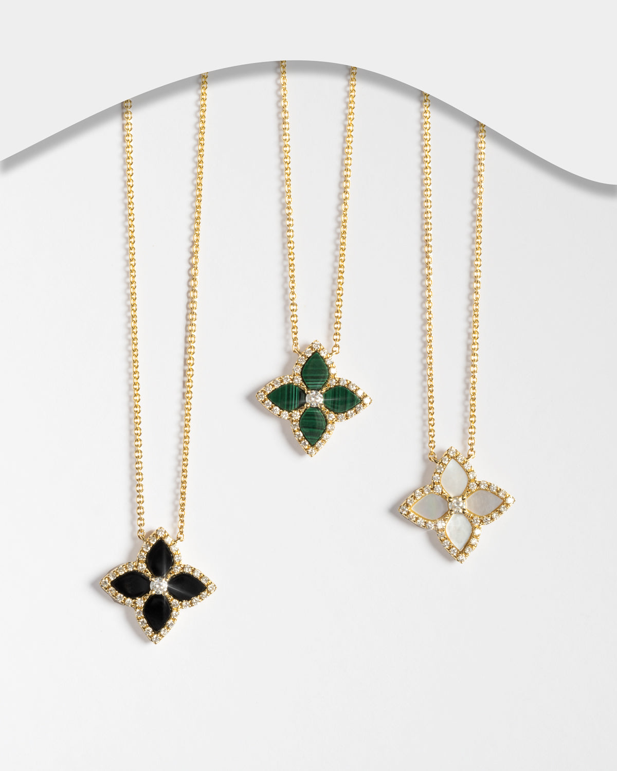 Three 18k yellow gold floral pendant necklaces with diamond halos, shown in malachite, mother of pearl, and onyx from the Flora collection.