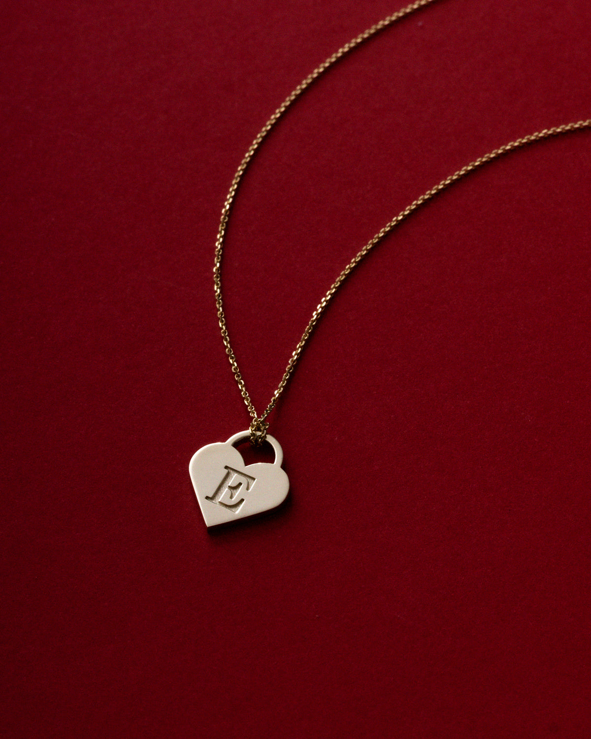 e heart letter pendant by claude and me jewellery on red background