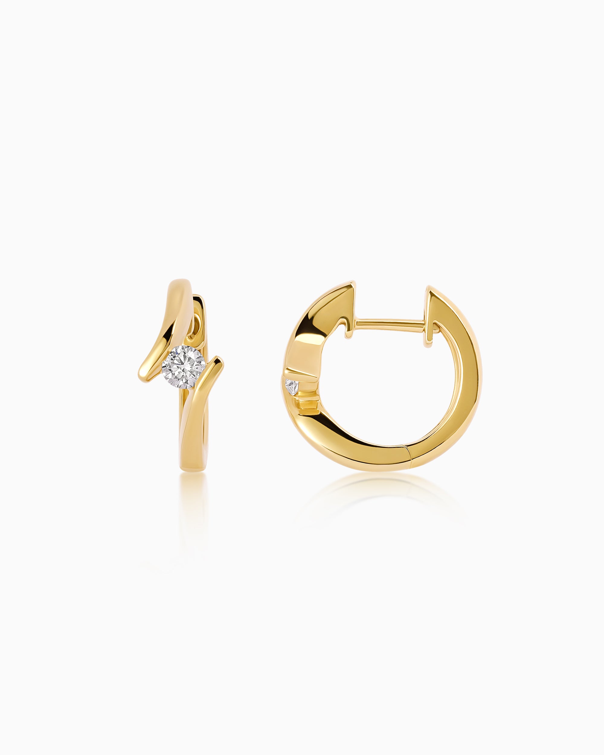 Pair of 18k yellow gold huggie earrings with bypass-style curves, each set with a round brilliant diamond.