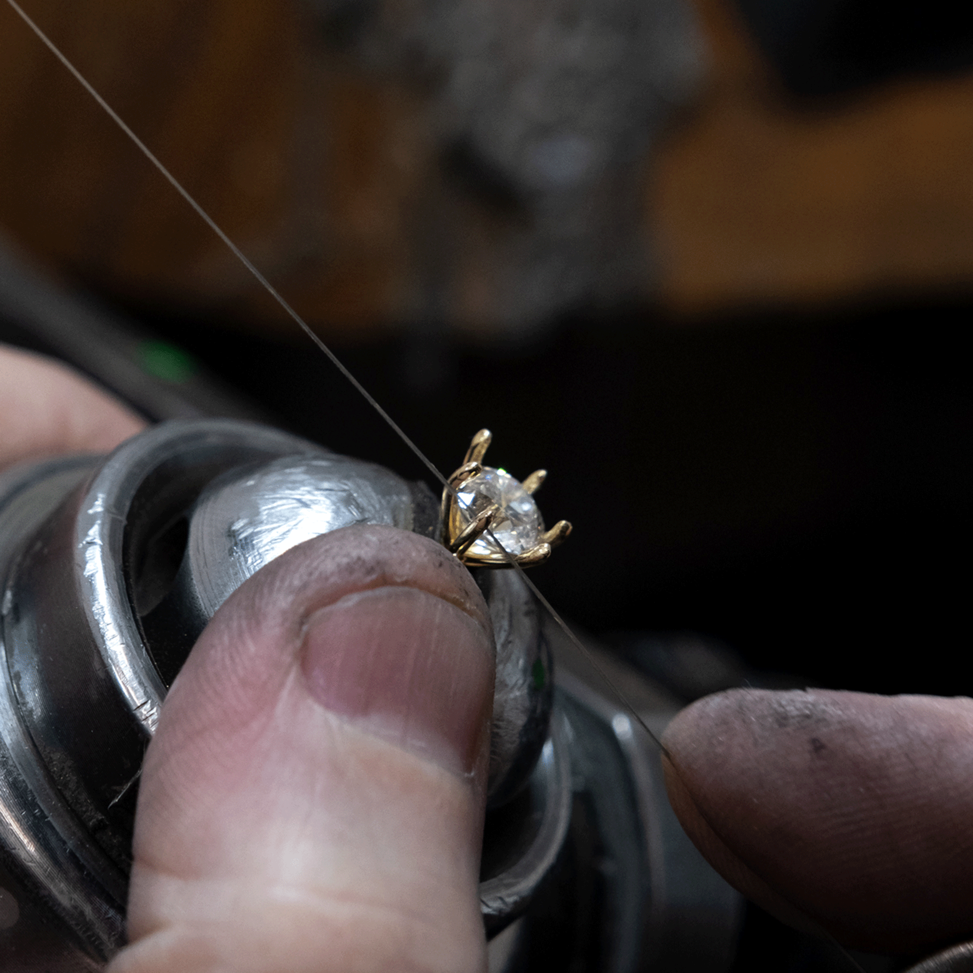 round diamond in a six claw setting being set by a jeweller