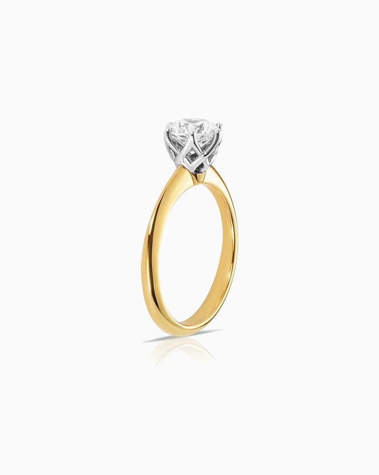 Side view of Round 6 claw basket solitaire engagement ring featuring 18 karat yellow and white gold by claude and me jewellery.
